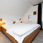 Doppel- oder Zweibettzimmer mit Balkon, komfortables Bett, Holzfußboden und helle Einrichtung