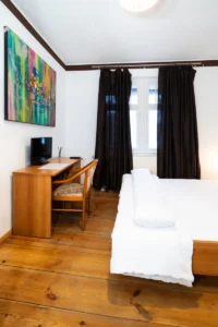 Zweibettzimmer mit Schreibtisch und TV in der Pension Kleinmachnow Wohnung 1